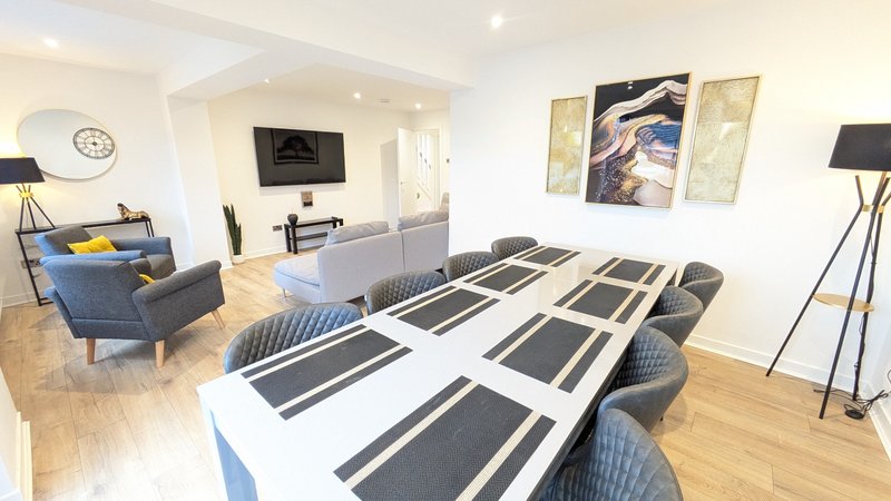 Open-plan office and lounge area with conference table, chairs, sofa and floor lamps