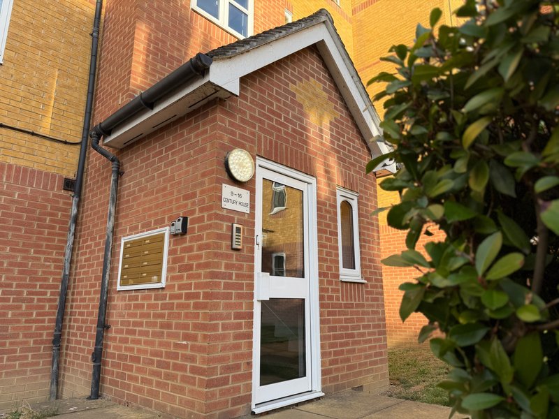 Red brick house exterior with white door, window, and climbing ivy on right side