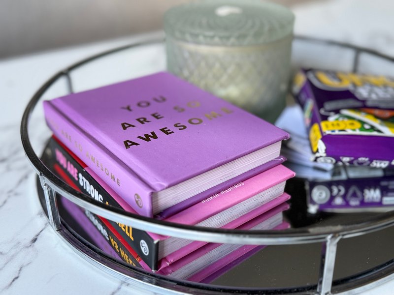 Decorative table tray with stacked books, candle, and small accessories