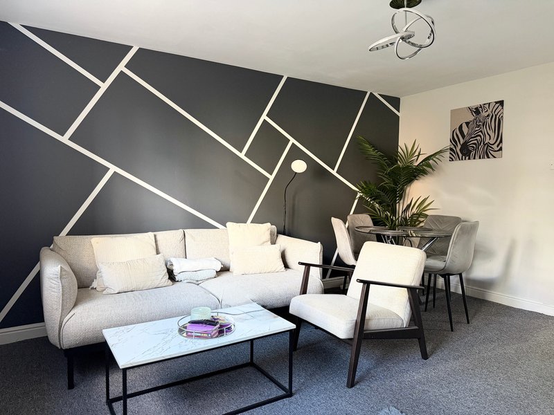 Modern living room with grey sofa, accent wall, potted plant and coffee table