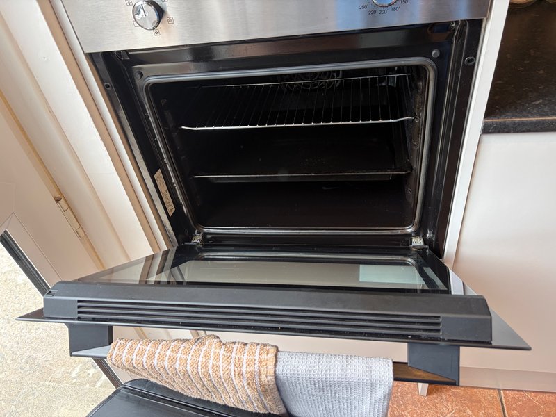 Open oven with kitchen towels draped over the door handle