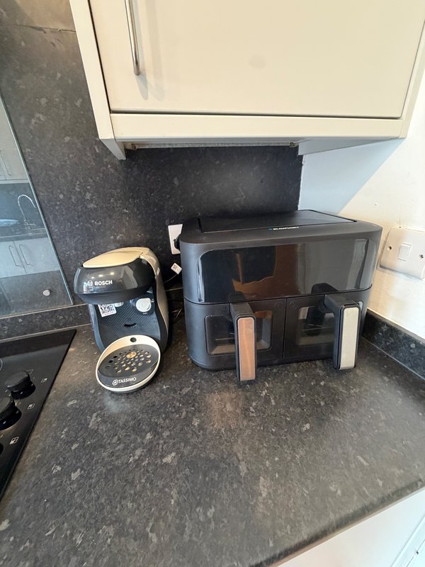 Kitchen countertop with coffee maker, black appliances and storage containers