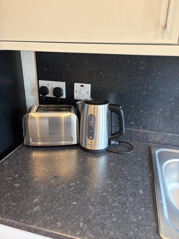 Kitchen counter with stainless steel toaster, electric kettle, and wall outlets