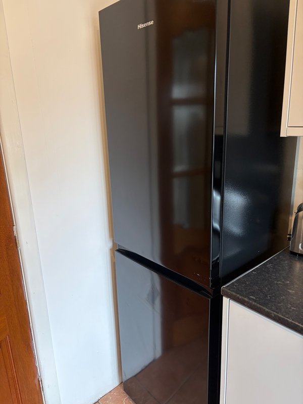 Black refrigerator with freezer compartment in modern kitchen with dark countertop
