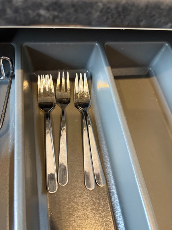 Kitchen drawer with cutlery organizer containing forks and other dining utensils