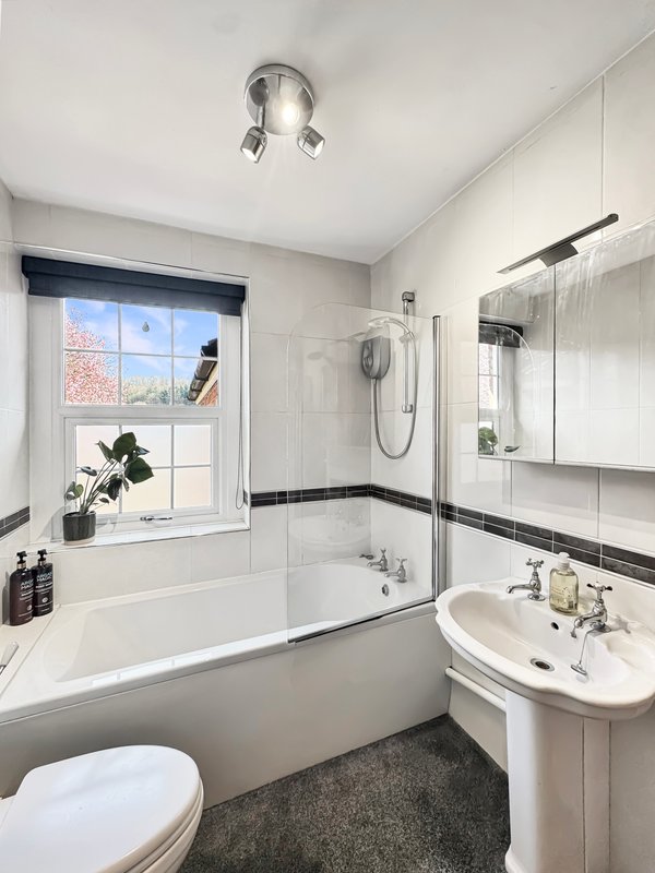 Modern bathroom with bathtub, pedestal sink, toilet, mirror and window