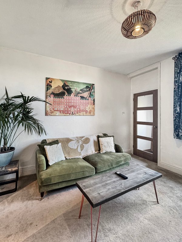 Modern living room with green sofa, framed artwork, potted plant, and coffee table