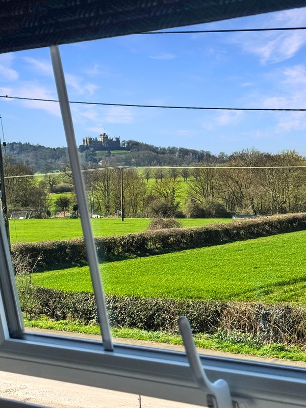 View through large window of rolling green fields, hedgerows and distant hills