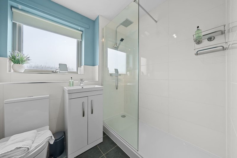 Modern bathroom with white vanity, glass shower enclosure, and blue-green wall trim