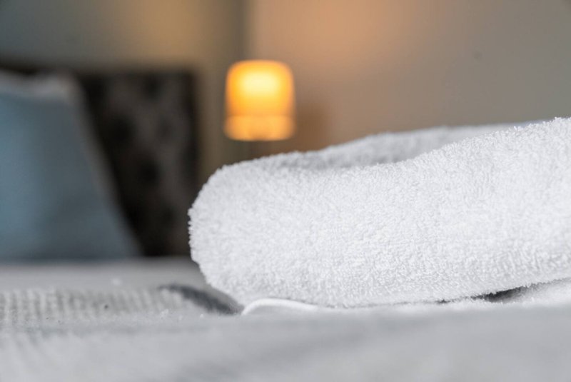 Close-up of folded white towels on bed with blurred bedroom background