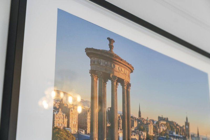 Framed photograph of classical columned monument and city skyline at sunset