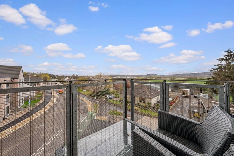 Elevated balcony view overlooking countryside with rolling hills and scattered buildings