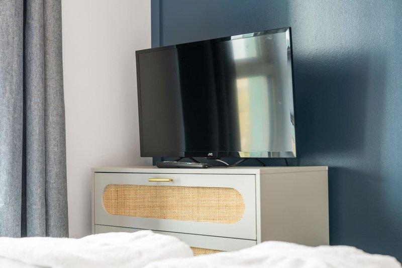 Bedroom with wall-mounted TV above low wooden cabinet with rattan door detail