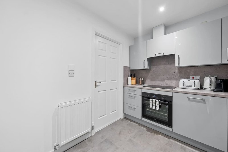 Modern kitchen with white cabinets, built-in oven, and grey tile flooring
