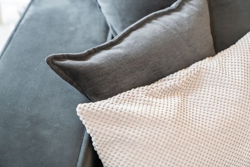 Close-up of sofa with grey upholstery and cream textured cushions