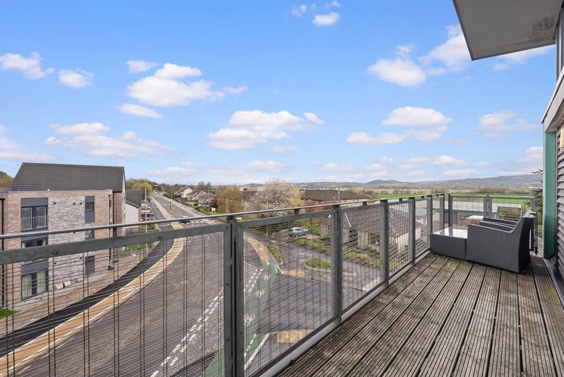 Elevated balcony with metal railing overlooking residential neighborhood and countryside