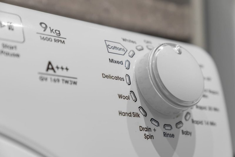 Close-up of washing machine control panel with dial and cycle settings