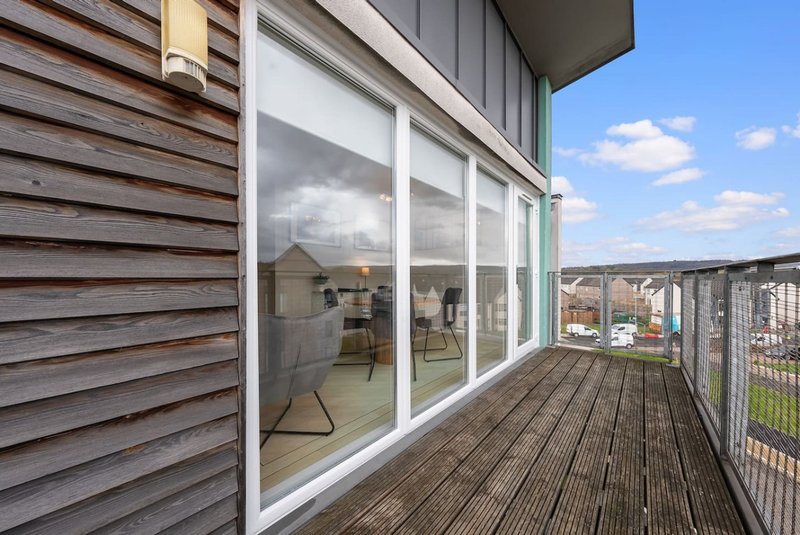 Balcony with wooden decking, large windows, metal railings and cityscape view