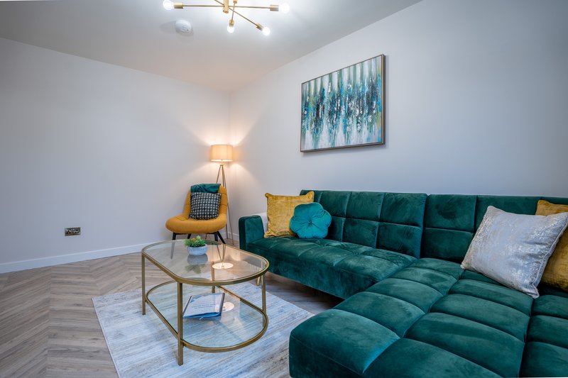 Modern living room with green sectional sofa, round coffee table, floor lamp and wall art