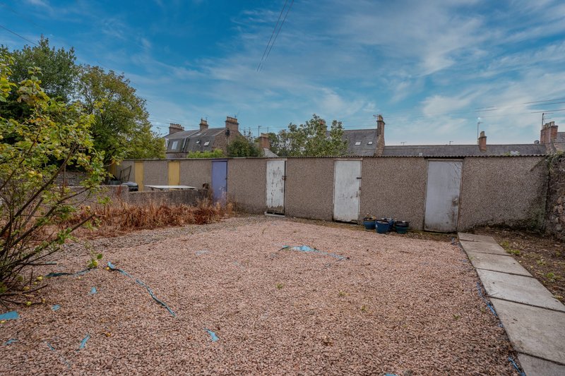 Rear garden with gravel patio, brick boundary wall, and terraced housing backdrop