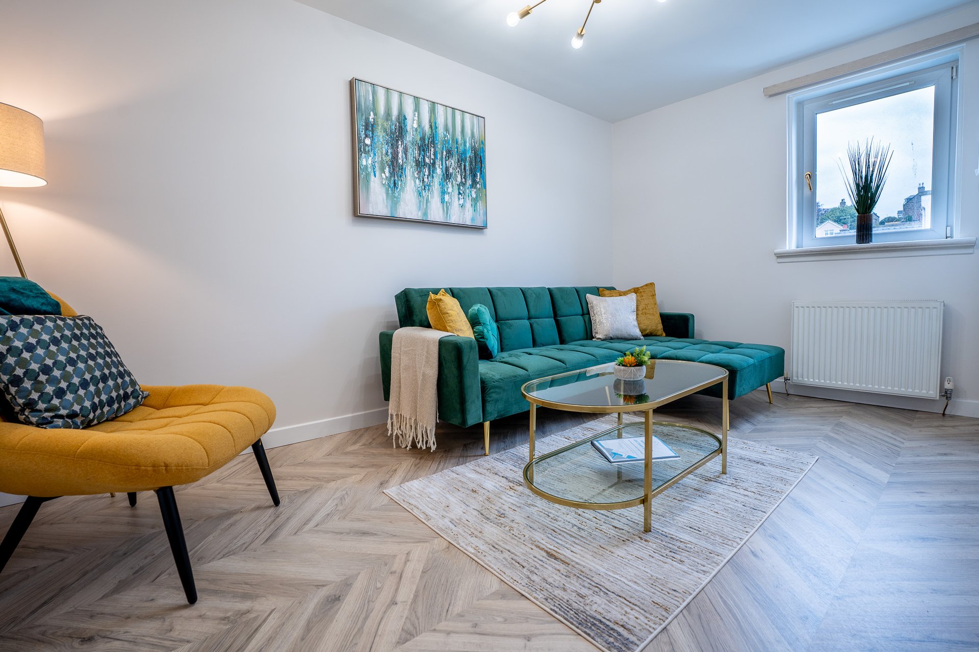 Modern living room with teal sofa, yellow armchair, coffee table and wall art