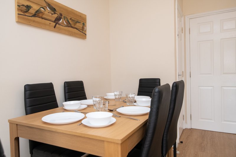 Dining room with wooden table, black chairs, place settings, and wall art