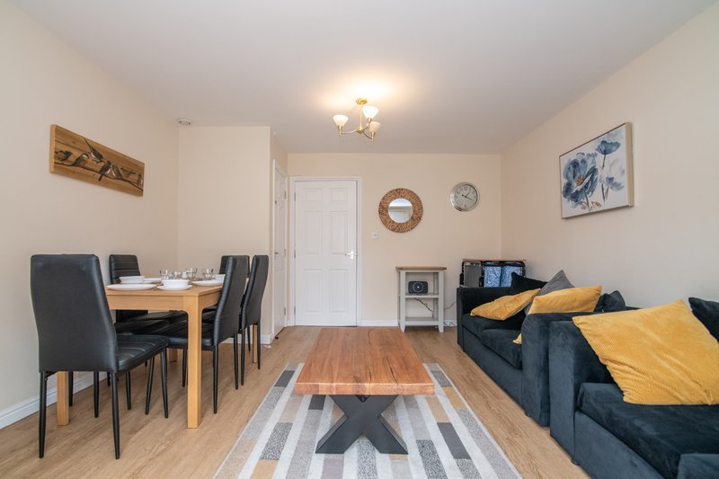 Open-plan living and dining area with sofa, dining table, wooden floor and wall art