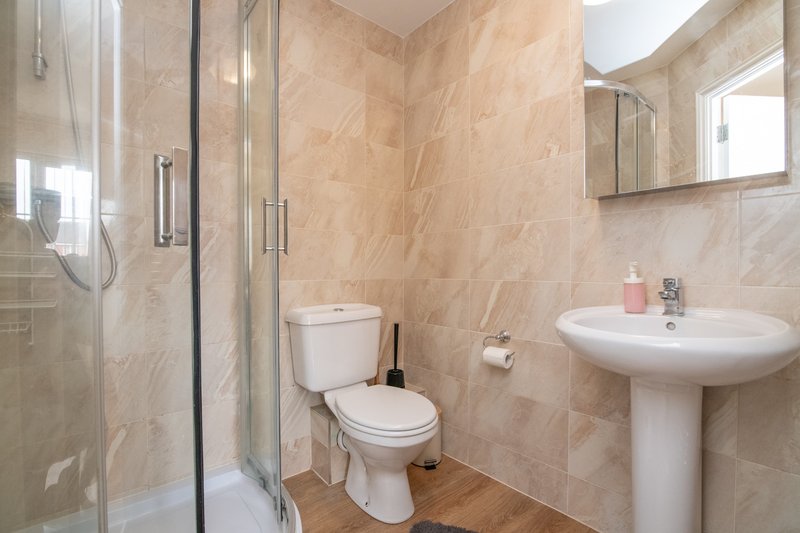 Bathroom with shower enclosure, toilet, pedestal sink, mirror and wooden flooring