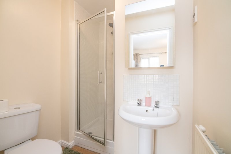 Bathroom with toilet, pedestal sink, mirror, and shower enclosure