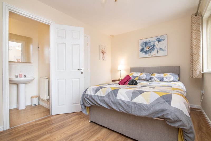 Bright bedroom with double bed, ensuite bathroom, wooden flooring and window