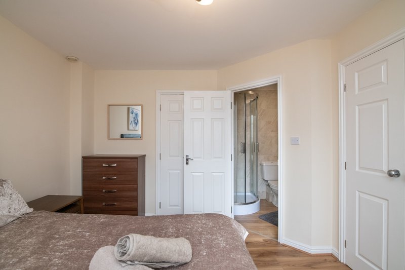 Bedroom with double bed, wooden dresser, ensuite bathroom with walk-in shower