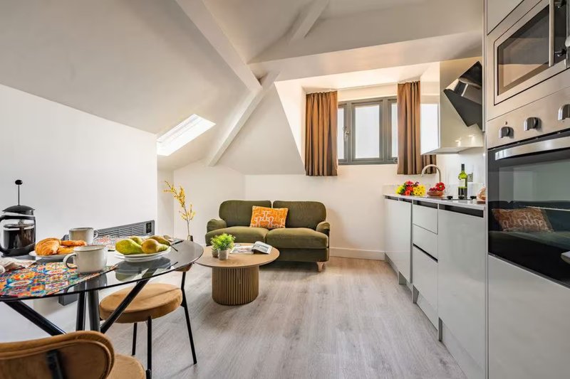 Open-plan kitchen and living area with dining table, sofa, and modern appliances