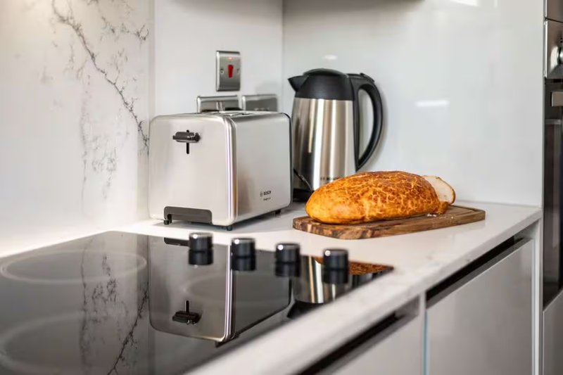 Modern kitchen counter with toaster, kettle, fresh bread and marble backsplash