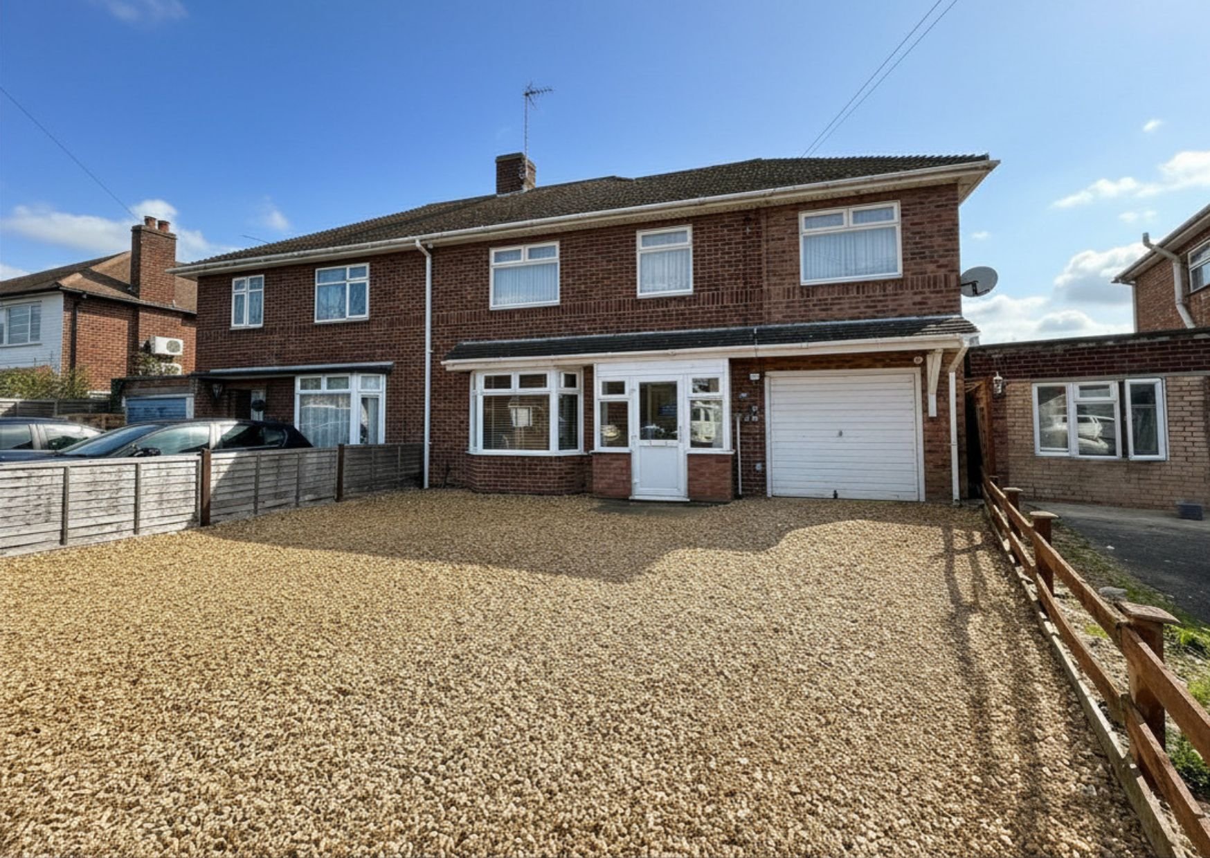 Brick semi-detached house with driveway, garage, and front garden