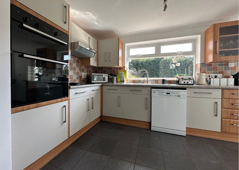 Modern kitchen with wooden cabinets, black built-in oven, white countertops and stainless steel appliances