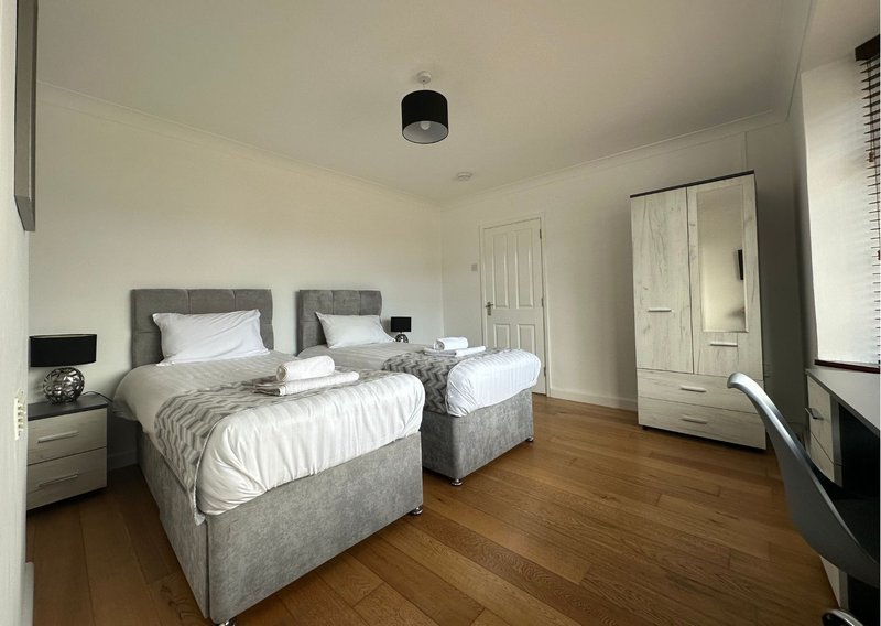 Bright bedroom with two single beds, wooden flooring, wardrobe and bedside tables