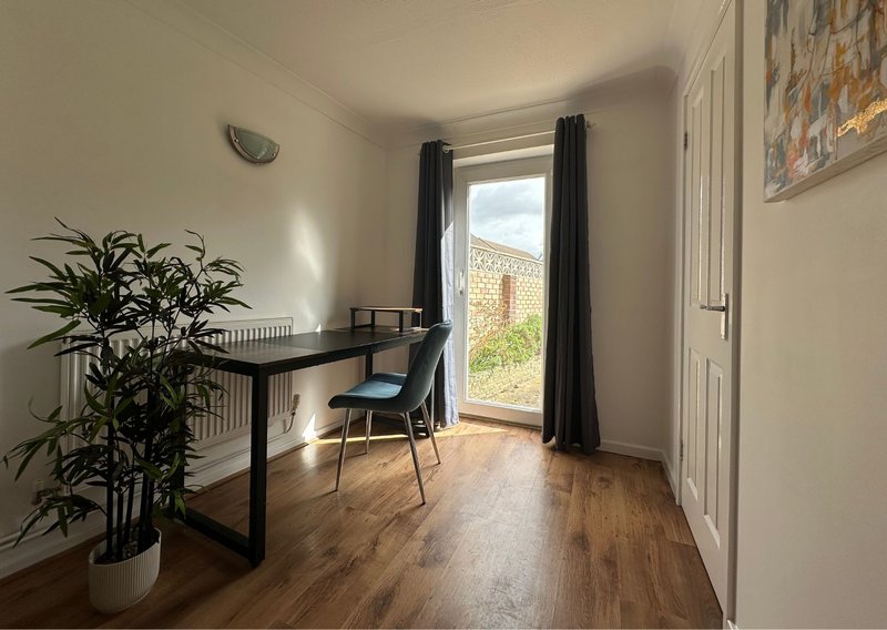 Bright home office with desk, chair, potted plant and door to garden