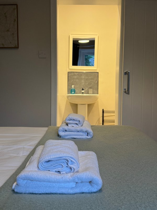 Bathroom vanity with illuminated mirror, shelving, and folded blue towels displayed on counter