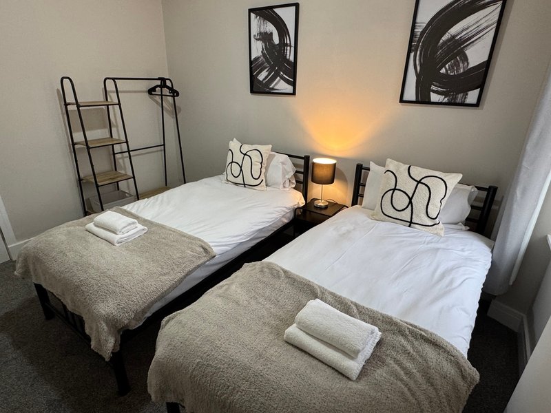 Twin bedroom with two single beds, white bedding, decorative wall art, and bedside lamps