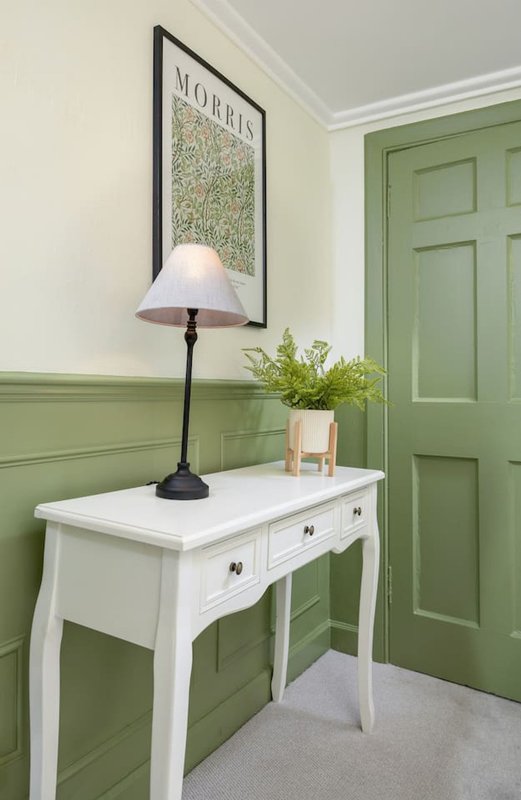 Hallway with white desk, black table lamp, framed map print, and green paneled door
