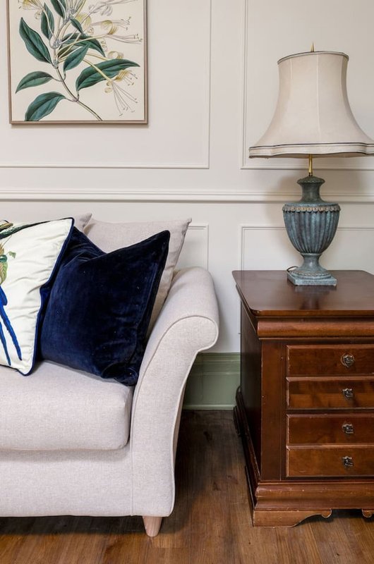 Living room with cream armchair, navy cushion, wooden side table and table lamp