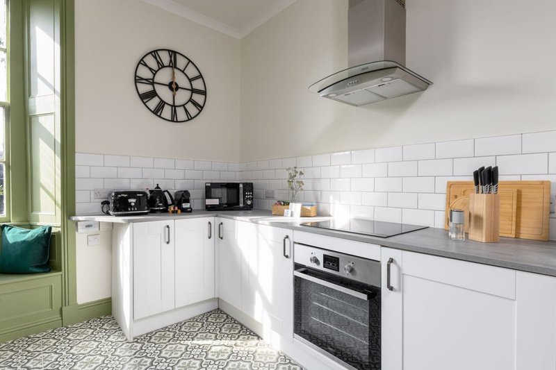 Modern white kitchen with subway tile backsplash, stainless steel appliances, and patterned floor tiles