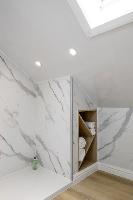 Modern bathroom with marble-effect shower enclosure, skylight, and built-in storage shelving