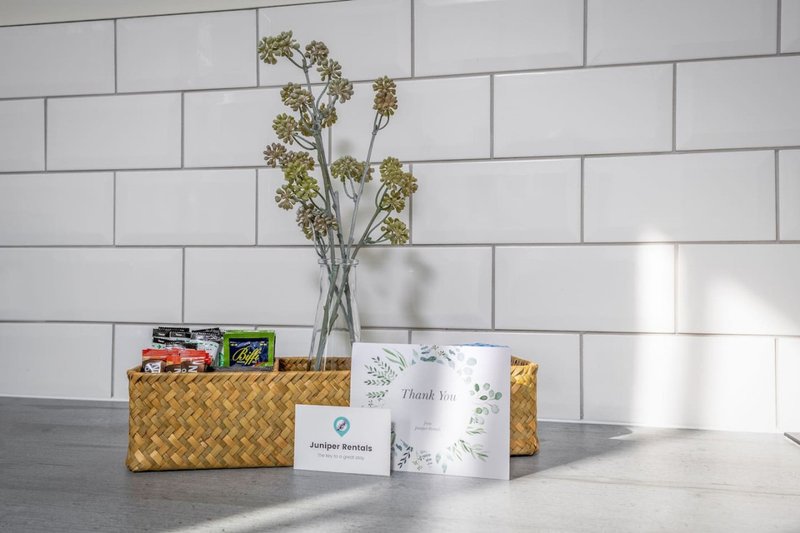 Kitchen counter with woven basket, dried flowers in glass vase, canned goods and decorative card