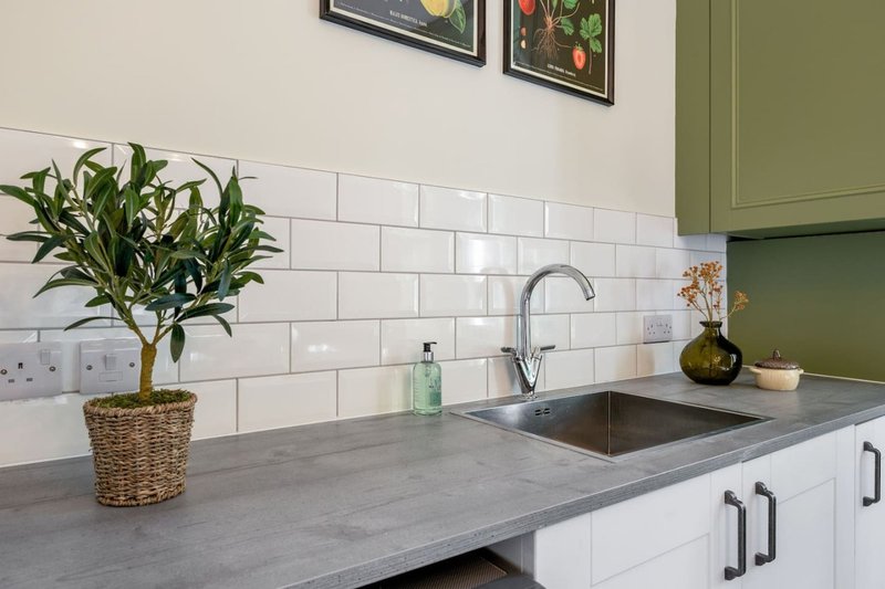 Modern kitchen with white subway tile backsplash, gray countertop, potted plant and framed artwork
