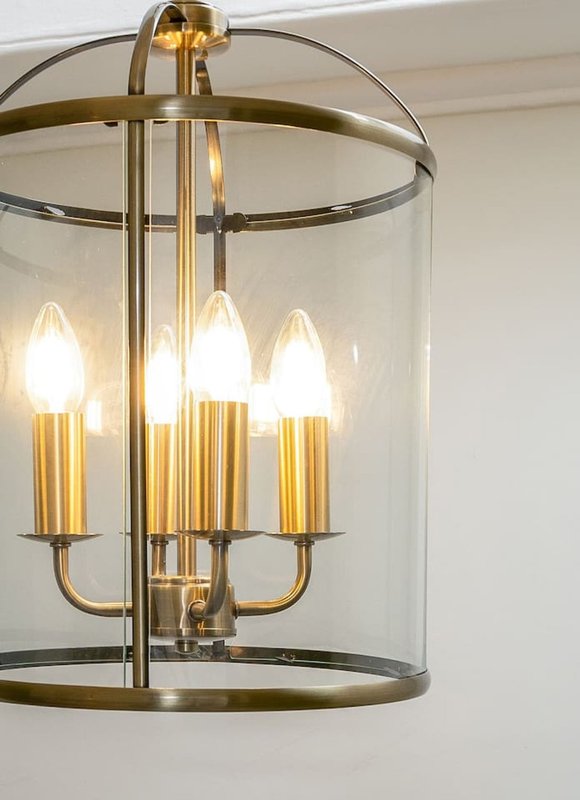 Gold and brass cylindrical pendant light fixture with four illuminated candle-style bulbs
