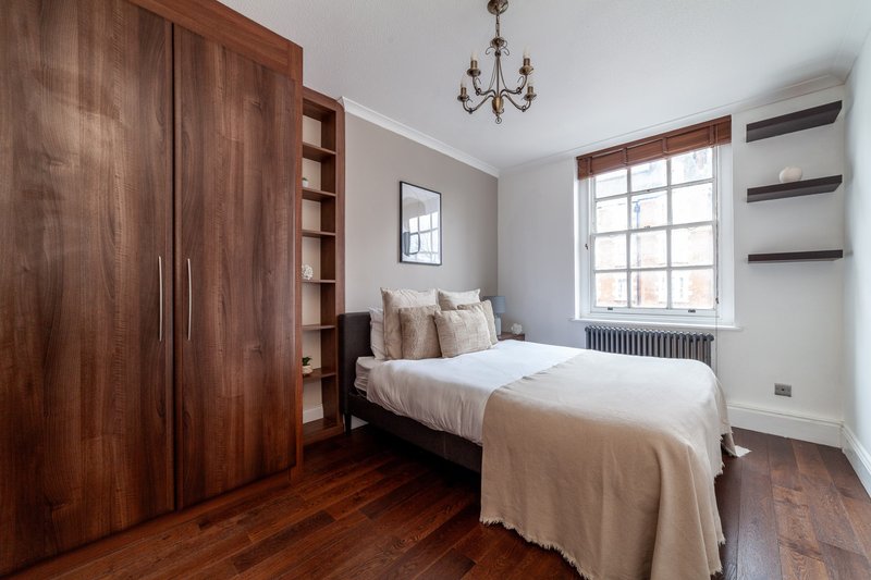 Bedroom with single bed, wooden wardrobe, hardwood floor and large window