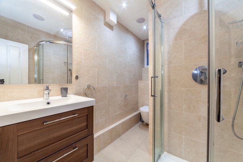 Modern bathroom with walk-in shower, vanity sink, mirror and wooden cabinetry