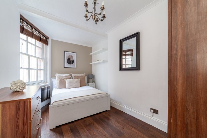 Bright bedroom with single bed, wooden floor, framed wall art and window with shutters