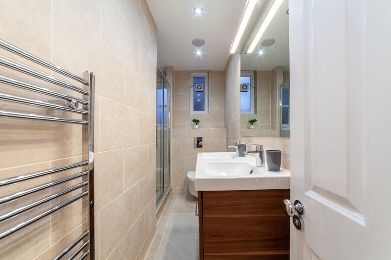 Modern bathroom with sink, mirror, heated towel rail and walk-in shower enclosure